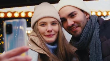 Genç çift gece Noel pazarında selfie çekiyor.