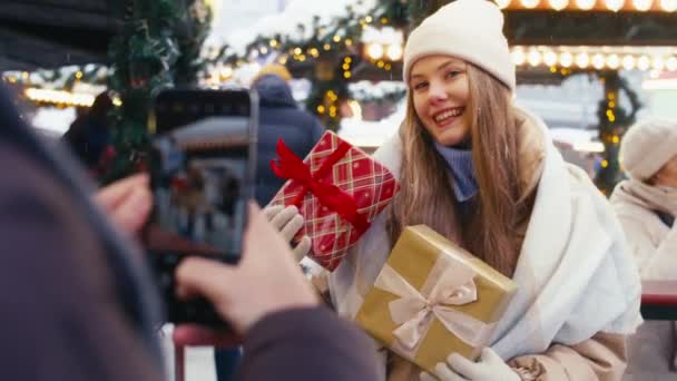 クリスマスマーケットの間に彼のガールフレンドの写真を撮る男 — ストック動画
