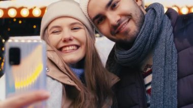 Genç çift gece Noel pazarında selfie çekiyor.