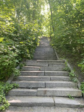 Şehirdeki dolambaçlı merdivenlerin manzarası, tepeye çıkan parktaki uzun taş basamaklar.