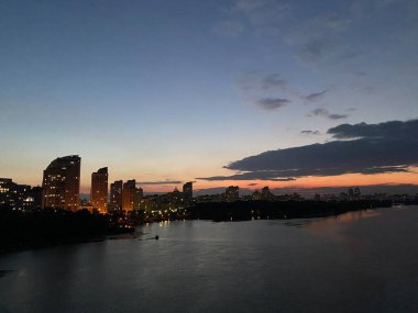 Gölün kıyısında güzel bir gün batımı şehrin arka planında ördekler