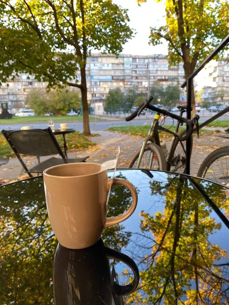 a cup of tea on the background of an autumn city and a bicycle