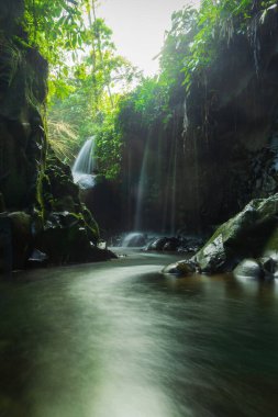 Kuzey Bengkulu 'daki Lorong Watu şelalesiyle Endonezya' nın cazibesini ziyaret edin. Taş duvarlarla kaplı dar bir sokak, Şelalede sabah ışığı parlıyor