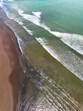 Endonezya sahilinin doğal manzarası, açık bir sabahta beyaz kum ve mavi deniz.