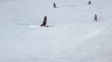 Geniş bir kayak yamacında güneşli bir gün. Kayak merkezi Jasna, Slovakya 'da. Birkaç kayakçı ve snowboardcu yavaş hareket ediyor. Yavaş çekim