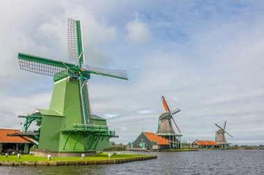 Hollanda 'da. Zaanse Schans 'ta yaz günü. Nehir kıyısında eski yel değirmenleri