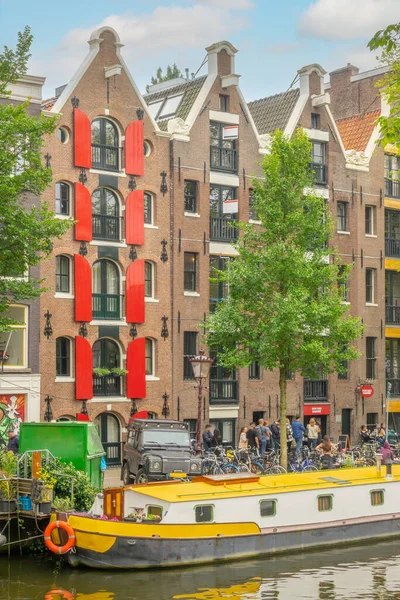 네덜란드 암스테르담 운하의 건물들이 있습니다 주거용 바지선 자전거 사람들은 빵집에서 — 스톡 사진