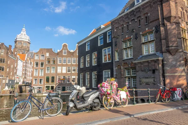 네덜란드 암스테르담에서의 운하를 가로지르는 다리의 가장자리 근처에 스쿠터와 자전거가 있었다 — 스톡 사진