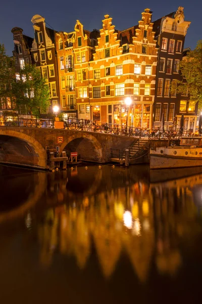 オランダだ アムステルダム運河の夜 ライトでオランダの家を踊る 屋外テーブル付きのバー 係留されていた古いボート — ストック写真