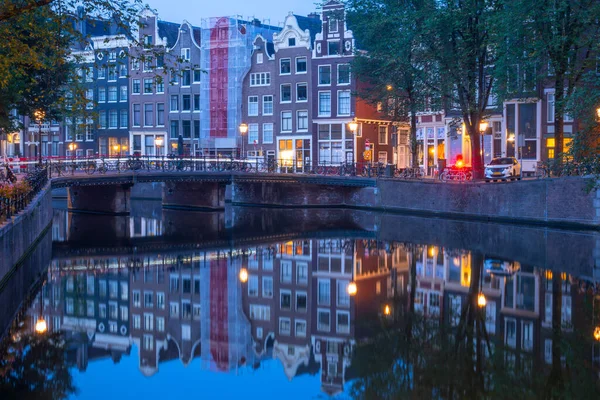 オランダ ストーンバンクとアムステルダム運河の架け橋 駐車した自転車がたくさん 夜明け前の水の中の朝の反射 — ストック写真