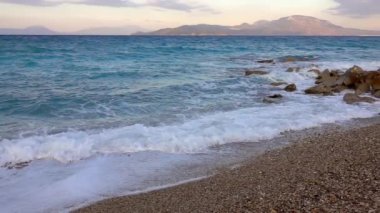 Akşam çakıl taşı plajı. Gelgit deliği. Küçük dalga ve köpük. Yavaş çekim