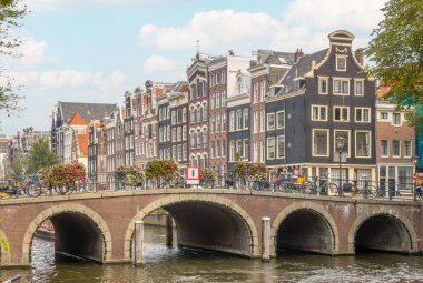Hollanda 'da. Amsterdam Kanalı 'ndaki eski taş köprü. Toprağın üzerinde dans eden tipik Hollandalı evleri.