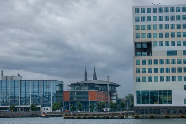 Hollandiában Felhős Nap Amszterdamban Modern Épületek Vízparton Stock Kép
