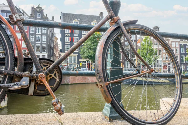 네덜란드 암스테르담의 운하에서 여름날 울타리 더러운 오래된 자전거 스톡 사진