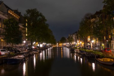 Hollanda 'da. Amsterdam 'da bir yaz gecesi. Fenerler ve park halindeki arabalar. Kanalın kıyısına demirlemiş tekneler