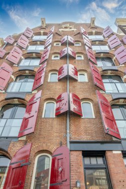 Hollanda 'da. Amsterdam 'ın orta bölgesinde kırmızı panjurlu tipik bir binanın cephesi