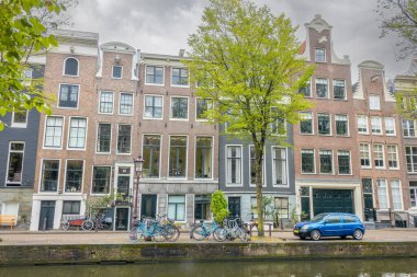 Hollanda 'da. Amsterdam Kanalı 'nın yaz seddindeki tipik binaların cepheleri. Bulutlu bir gün