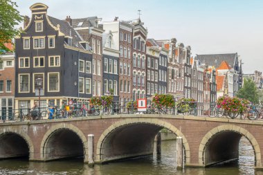 Hollanda 'da. Amsterdam seti üzerinde dans eden tipik Hollandalı evleri. Kanaldaki eski taş köprü