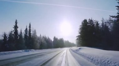 Fin Laponyası. Kış ormanı yolunda araba sürüyorum. Mavi gökyüzünde güneş ve hafif kar.