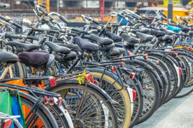 Hollanda 'da. Gündüz Amsterdam. Otoparkta birçok bisiklet var. Odaklanamayan bir sokak arkaplanı üzerinde.