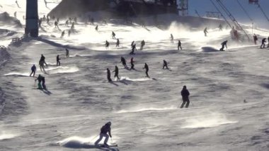 Kış Slovakya. Jasna kayak merkezindeki Tatras 'ta güneşli bir gün. Kayakçılardan oluşan bir kalabalık kayak yamacından aşağı iniyor. Parlak güneşli hava. Yavaş çekim