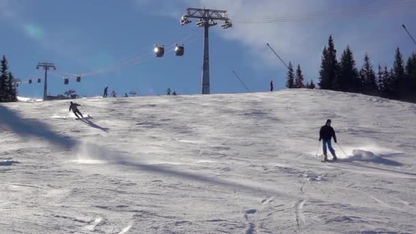 冬のスロバキア ジャスナスキー場のタトラで晴れた日 いくつかのスキーヤーは バックグラウンドでスキーリフトで斜面を下ります 明るい晴れた天気 スローモーション — ストック動画