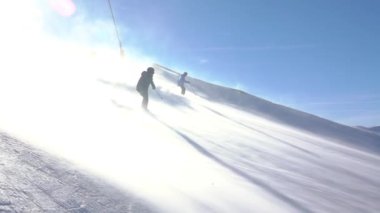 Jasna kayak merkezindeki Slovak Tatras 'ta güneşli bir kış günü. Kar fırtınası. İki kayakçı yamaçtan aşağı iniyor. Yavaş çekim