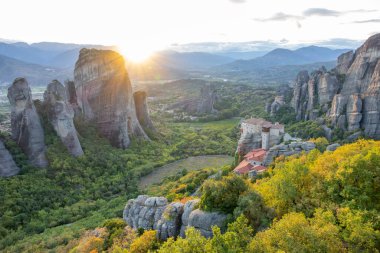 Yunanistan. Meteora 'daki yeşil vadide gün batımı ışınları. Kayadaki manastır.