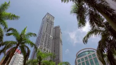 Singapur 'da güneşli bir gün. Gökdelenler ve mavi gökyüzüne karşı palmiye ağaçları. Alt görünüm