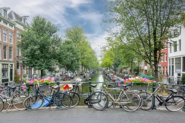 阿姆斯特丹的夏日 蓝天中的云彩 几辆自行车停放在运河上一座桥的栏杆附近 图库图片