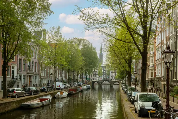 在阿姆斯特丹市中心的一条运河上度过的夏天 许多船只和汽车停泊在堤岸上 图库图片