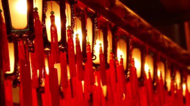 Karanlık ahşaptan oyulmuş dekoratif fenerler boyalı camlar ve altın örgülü kırmızı püsküller Budist tapınağında yavaşça sallanıyor.