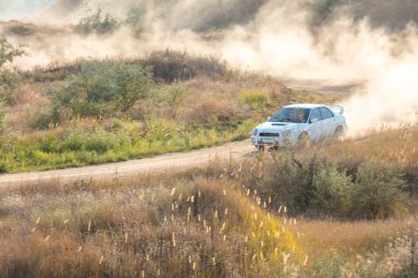 Güneşli bir yaz günü. Toprak rali pistinde geniş bir dönüş. Araba toz bulutları yaratır.