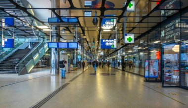 Hollanda, Amsterdam - 27 Eylül 2021: Amsterdam Merkez İstasyonu içinde. Bir sürü dükkan. - İnsanlar. Tren ve feribot için aynalı tavan ve elektronik zaman çizelgeleri.