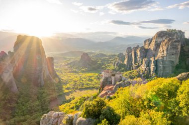 Yunanistan. Kalambaka 'nın yeşil vadisinde yaz günbatımı ışınları. Küçük bir kaya manastırı.