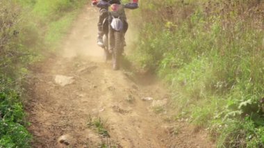 Güneşli bir yaz günü. Tozlu bir patikada motosiklet süren Enduro binicisi. Yavaş çekim