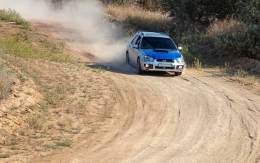 Güneşli bir yaz günü. Bir spor hatchback toprak yolda keskin bir dönüş yapar ve toz bulutu yaratır.