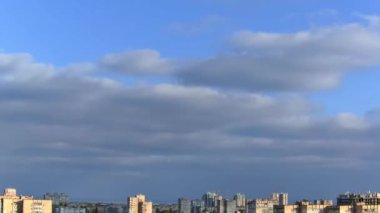 Güneşli bir yaz gününde şehrin çatıları. Bulutlar mavi gökyüzünde hızla koşup binalara gölge düşürüyor. Zaman aşımı