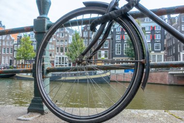 Hollanda 'da. Amsterdam 'da yaz günü. Kanal kenarına park edilmiş bisiklet tekerleği.