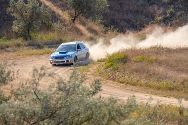 Bozkırlarda güneşli bir yaz günü. Bir rali arabası keskin bir viraja eğilir ve toprak bir yolda toz bulutu kaldırır.