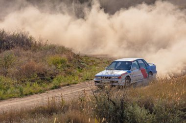Bozkırlarda güneşli bir yaz günü. Toprak bir virajda bir ralli aracının yarattığı büyük bir toz bulutu.
