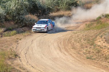 Bozkırlarda güneşli bir yaz günü. Bir rali arabası bir dönemece giriyor toprak bir yolda yuvarlanıp tozlanıyor.