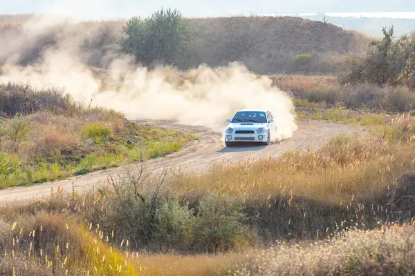 Bozkırlarda güneşli bir yaz günü. Beyaz spor araba toprak yolda toz bulutu kaldırıyor.