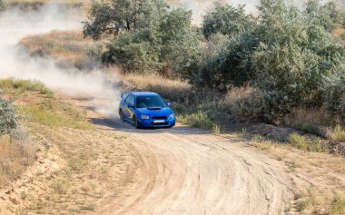 Bozkırlarda güneşli bir yaz günü. Bir rali arabası tozlu toprak bir yolda birkaç dönüş yapar.