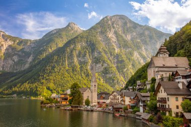 Avusturya yazı. Hallstatt 'ın küçük bir kasabasının mimarisi güneşli bir günde, Hallstatter Gölü kıyısında, ağaçlık ve kayalık dağlarla çevrili.