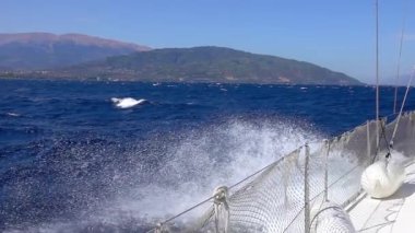 Güneşli ve rüzgarlı bir gün. Kıyıya yakın fırtınalı bir deniz. Beyaz yelkenli yat deniz dalgaları üzerinde süzülür ve bir püskürtme bulutu yaratır. Yavaş çekim