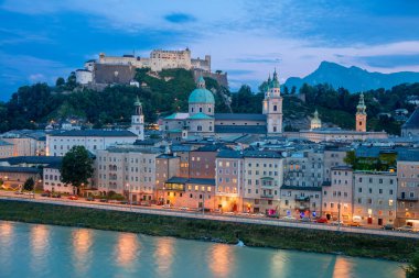 Avusturya, Salzburg 'da yaz alacakaranlığı. Akşam ışıklarıyla Hohensalzburg Kalesi ve Salzach Nehri seti manzarası