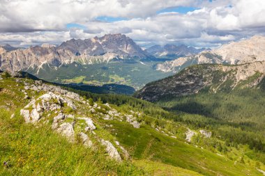 Avusturya Alplerinde güneşli bir yaz günü. Kayalık tepelerde desenli bulutlar. Altında küçük bir köy olan yeşil vadi
