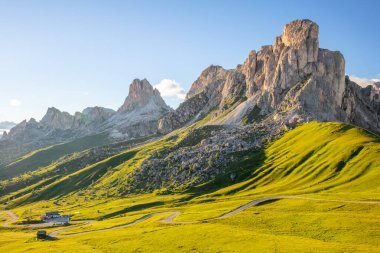 Avusturya Alplerinde güneşli bir gün. Kayalık tepelerin üstündeki mavi gökyüzü. Dolambaçlı yolu olan yeşil bir vadi. Mini otel, görkemli dağlarla çevrili.