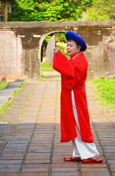 Hue, Vietnam - 24 Şubat 2023: Vietnamlı bir kadın Hue, Vietnam 'daki Imperial City' de geleneksel elbiseler içinde poz veriyor. Geleneksel ao dai elbisesini giyen ziyaretçiler Kraliyet Şehri 'ne ücretsiz giriş hakkı kazandılar..
